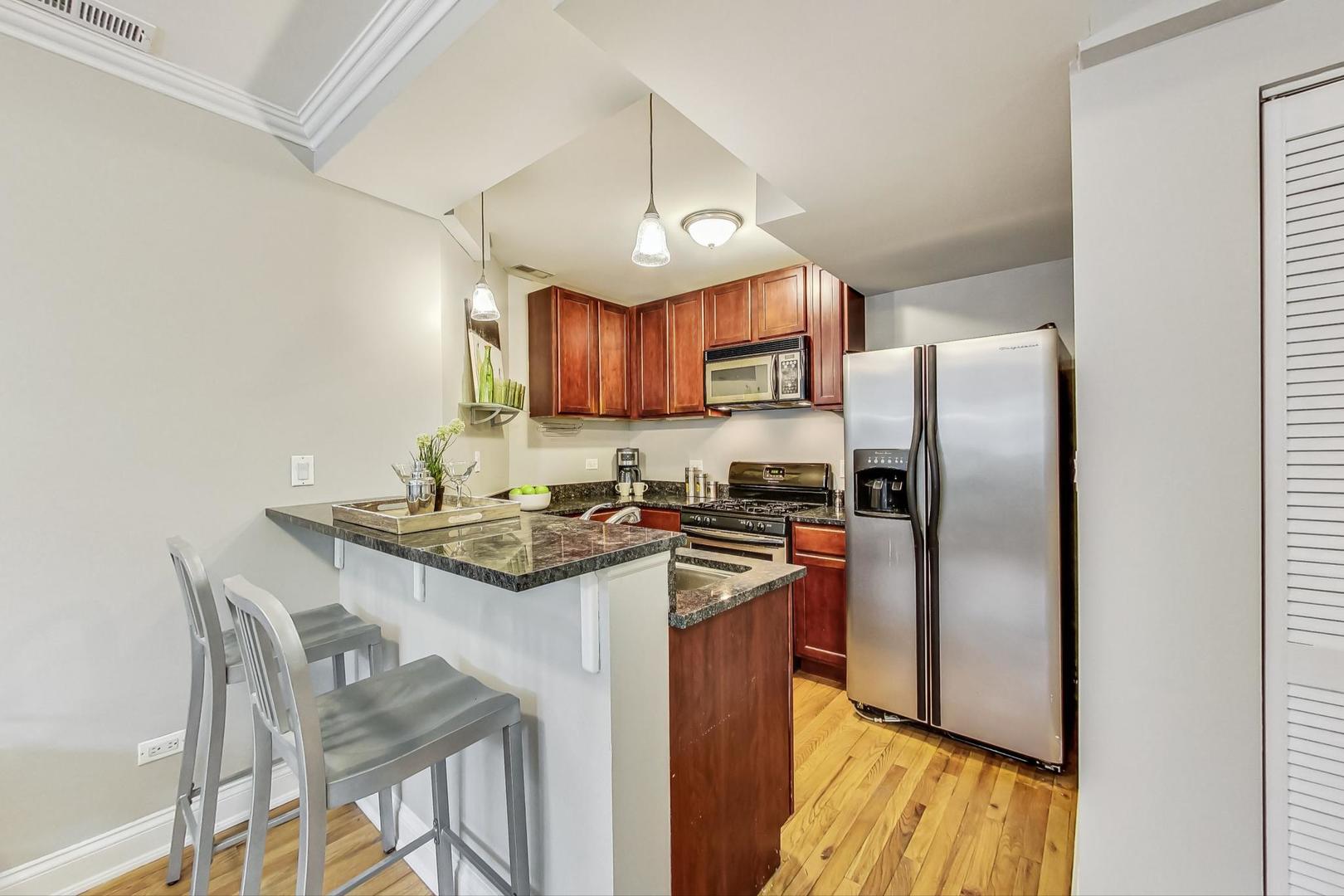 3734 North Clifton Avenue, Unit G Chicago, IL 60613 - Photo 10 of 27 a kitchen with stainless steel appliances granite countertop a sink a stove a refrigerator cabinets a dining table and chairs
