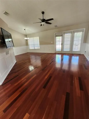 a view of empty room with wooden floor and fan