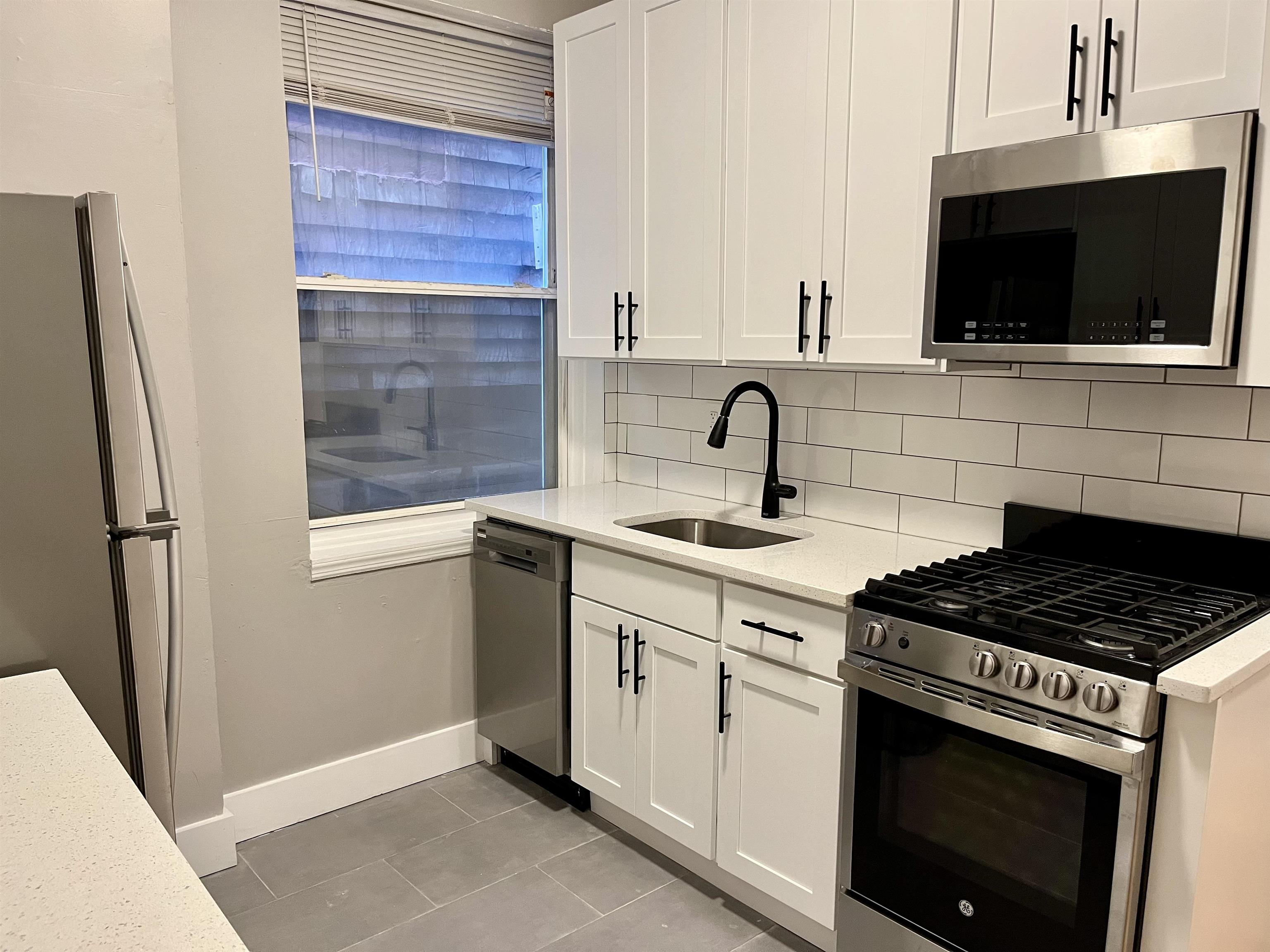 514 John F. Kennedy Boulevard, Unit 1 Bayonne, NJ 07002 - Photo 2 of 7 a kitchen with stainless steel appliances a stove microwave and a sink