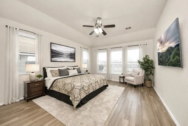 a spacious bedroom with a bed couch and windows