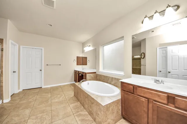 a spacious bathroom with a tub sink and mirror