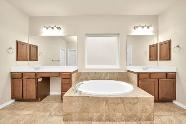 a spacious bathroom with a tub sink and mirror