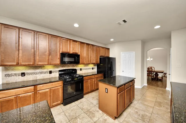a kitchen with stainless steel appliances granite countertop a stove top oven a sink and a refrigerator