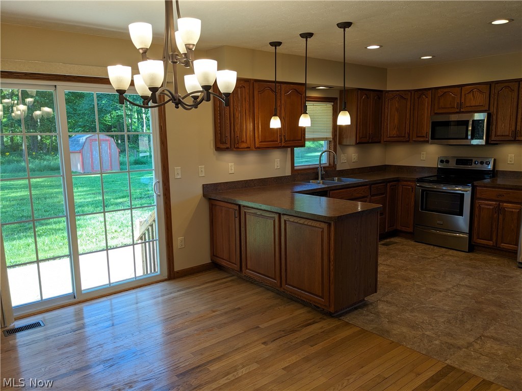 759 East Pleasant Home Road Wooster, OH 44691 - Photo 5 of 31 Kitchen featuring kitchen peninsula, an inviting chandelier, hanging light fixtures, sink, and appliances with stainless steel finishes