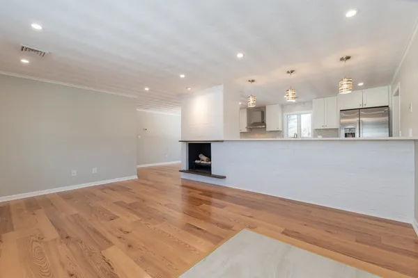 a view of a kitchen with kitchen island a sink wooden floor and stainless steel appliances