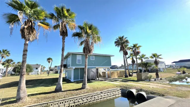 a view of a house with a yard and palm trees