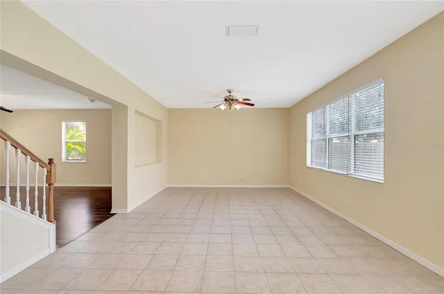 an empty room with windows and chandelier fan