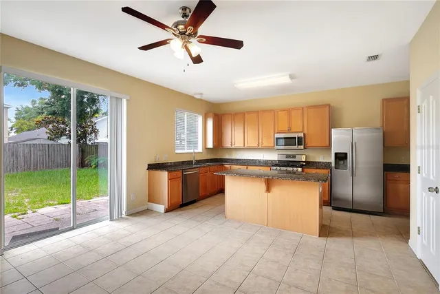 a kitchen with stainless steel appliances kitchen island granite countertop a refrigerator a sink a stove a oven with a dining table and chairs