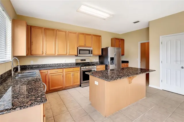 a kitchen with stainless steel appliances granite countertop a stove a sink and a refrigerator
