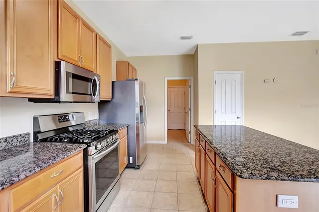 a kitchen with stainless steel appliances granite countertop a stove a sink and a microwave