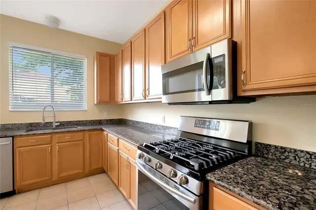 a kitchen with stainless steel appliances granite countertop a stove a sink and a microwave