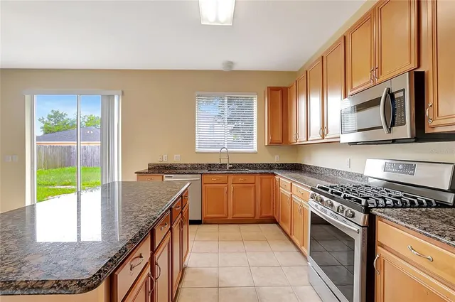 a kitchen with stainless steel appliances granite countertop a stove a sink and a microwave
