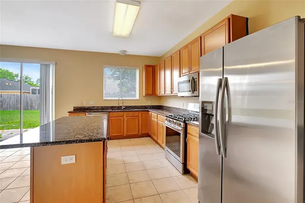 a kitchen with stainless steel appliances granite countertop a refrigerator a sink and a stove