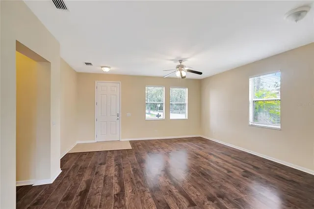 a view of an empty room with wooden floor and a window