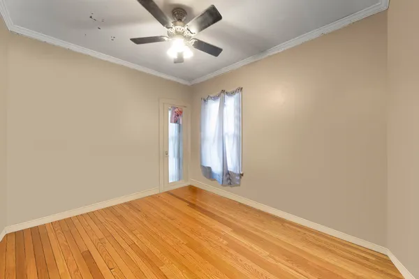 an empty room with a ceiling fan and wooden floor