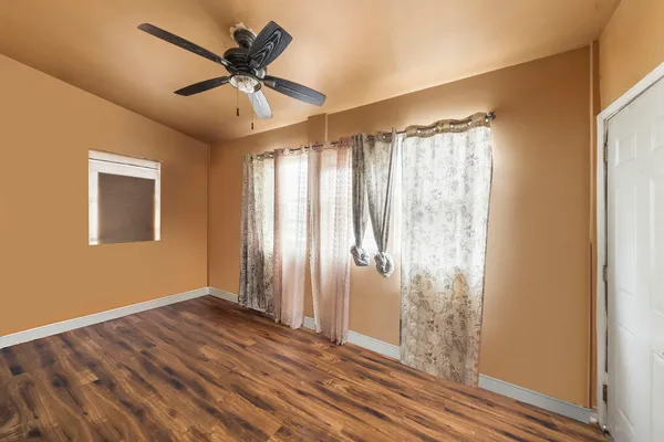 a view of an empty room with wooden floor and a window