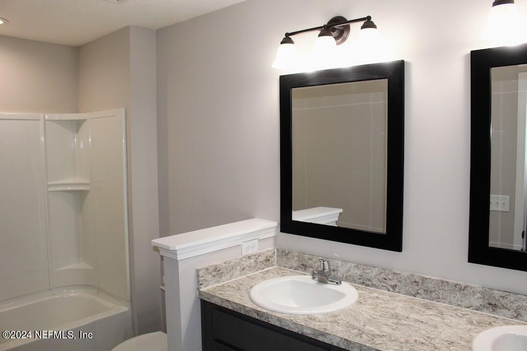 4152 Quiet Creek Loop, Unit 134 Middleburg, FL 32068 - Photo 23 of 42 a bathroom with a granite countertop sink and a mirror