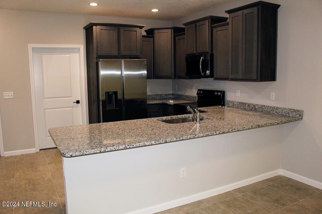4152 Quiet Creek Loop, Unit 134 Middleburg, FL 32068 - Photo 34 of 42 a kitchen with granite countertop a refrigerator and a sink