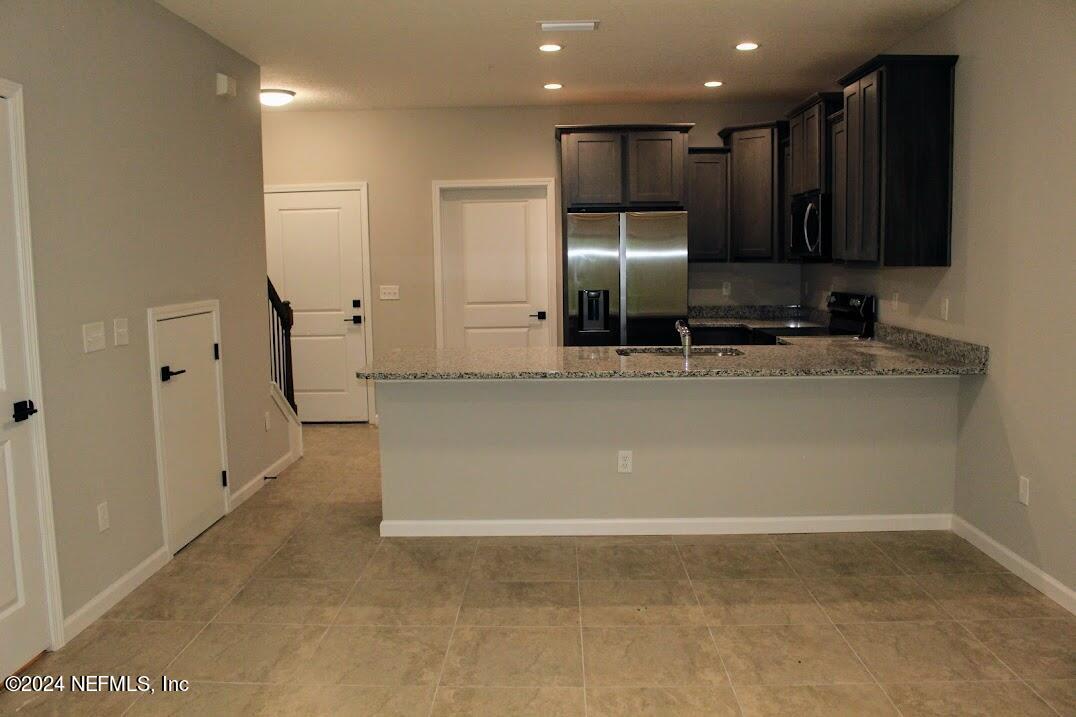 4152 Quiet Creek Loop, Unit 134 Middleburg, FL 32068 - Photo 7 of 42 a modern kitchen with stainless steel appliances granite countertop a sink a stove and a refrigerator