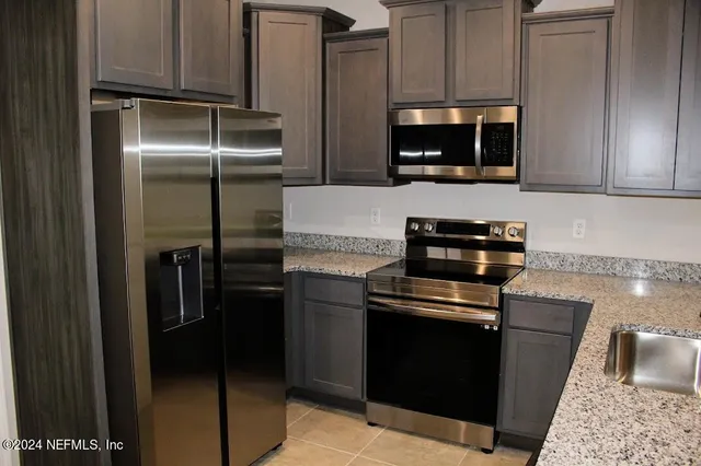 a kitchen with granite countertop a refrigerator stove and microwave