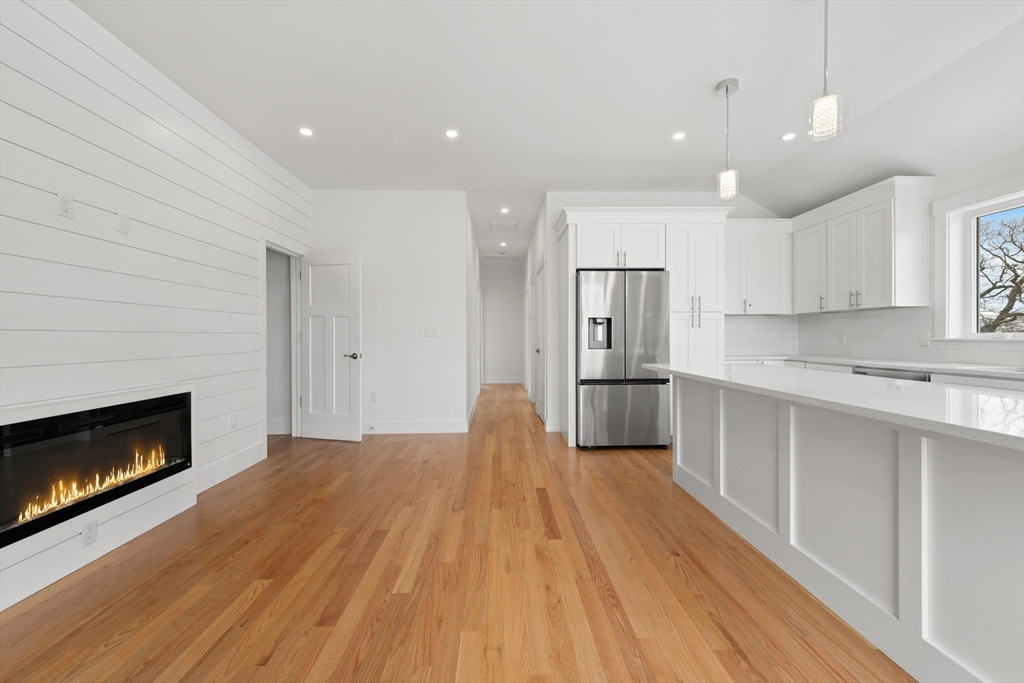 2 Old County Road, Unit 10 Salisbury, MA 01952 - Photo 8 of 27 a open kitchen with kitchen island a fireplace wooden floor and a window