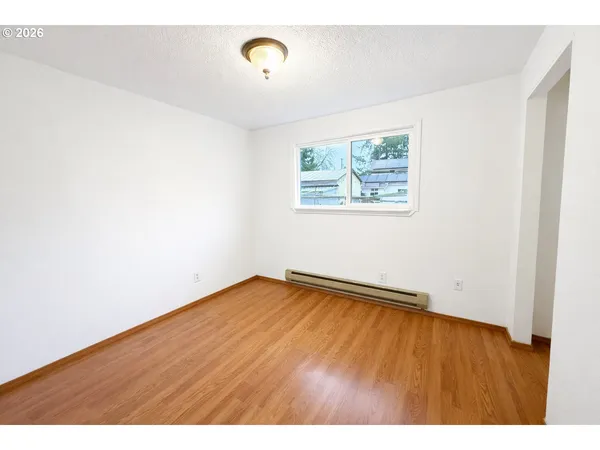 a view of an empty room with a window and wooden floor