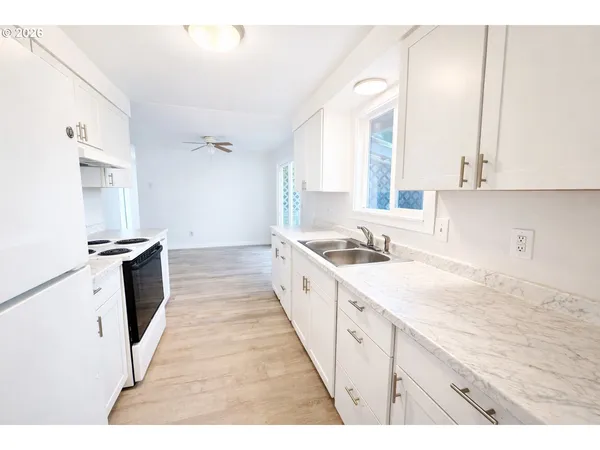 a large white kitchen with sink and a window