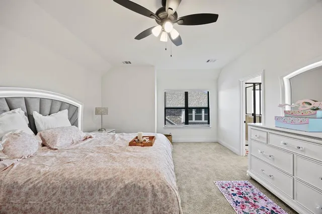 a bedroom with a large bed and a chandelier fan