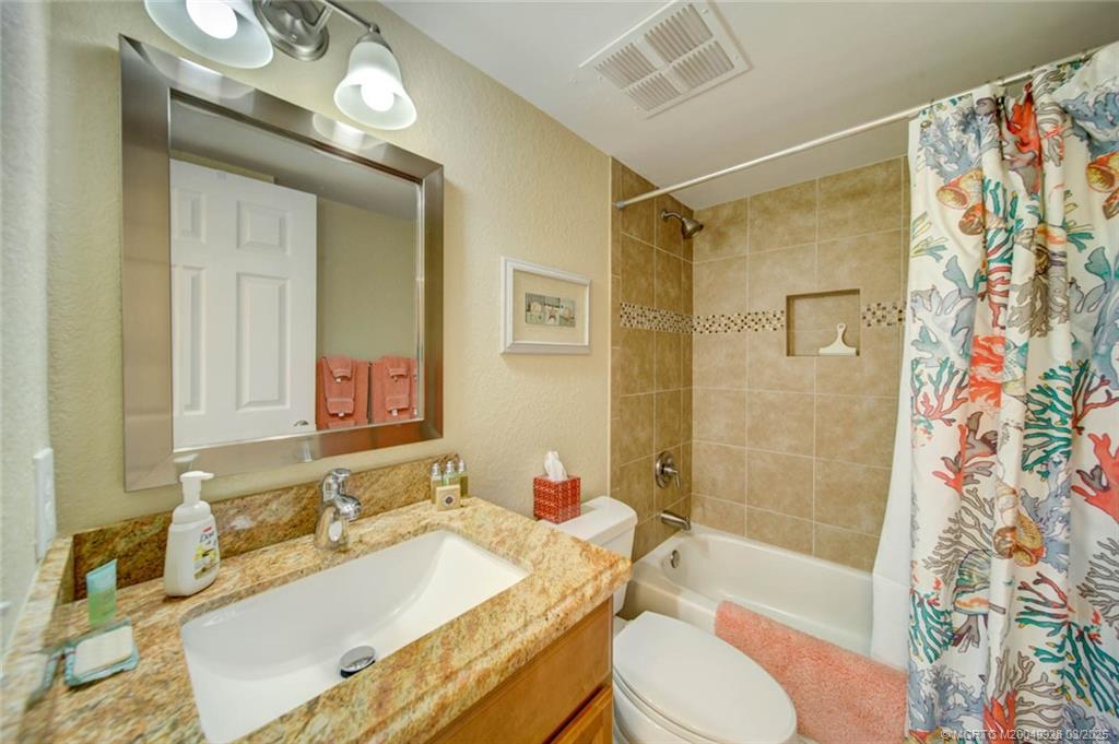 7380 South Ocean Drive, Unit 320 Jensen Beach, FL 34957 - Photo 28 of 39 a bathroom with a granite countertop sink toilet a mirror and shower
