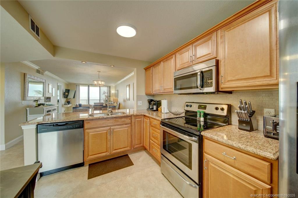 7380 South Ocean Drive, Unit 320 Jensen Beach, FL 34957 - Photo 9 of 39 a kitchen with stainless steel appliances granite countertop a stove a sink dishwasher and a microwave oven with cabinets