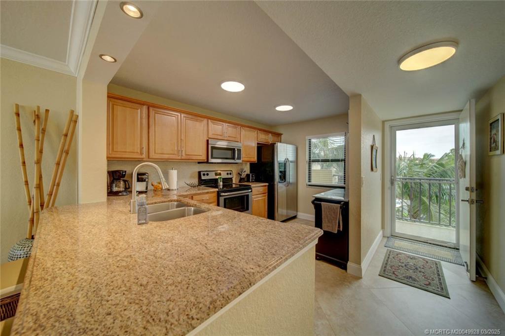 7380 South Ocean Drive, Unit 320 Jensen Beach, FL 34957 - Photo 10 of 39 a kitchen with sink a refrigerator and cabinets