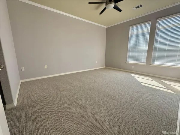 en empty room with windows and ceiling fan