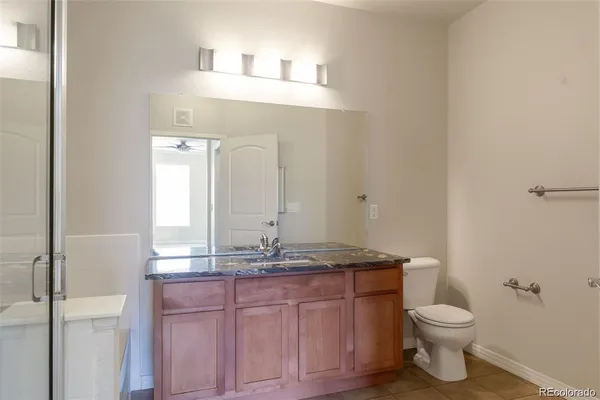 a bathroom with a granite countertop sink a toilet and a mirror