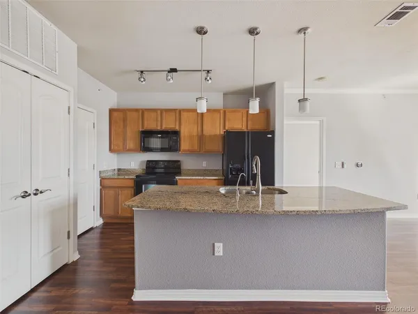 a kitchen with kitchen island a counter top a stove a sink and a wooden floors