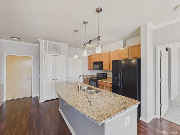 a kitchen with stainless steel appliances granite countertop a refrigerator a sink and wooden floor