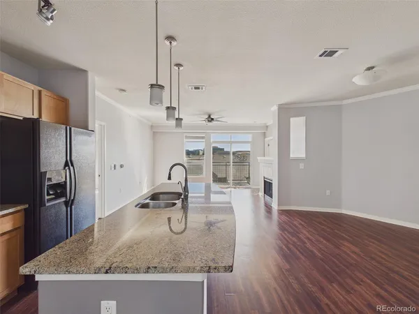 a kitchen with granite countertop a kitchen island hardwood floor sink stove and refrigerator