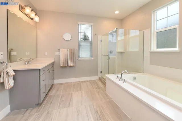 a spacious bathroom with a double vanity sink a mirror and a bathtub