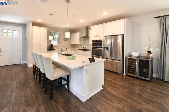 a kitchen with stainless steel appliances a dining table chairs stove refrigerator and microwave