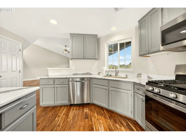 a kitchen with granite countertop a sink cabinets stainless steel appliances and a window