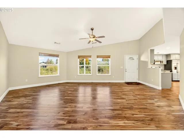 a view of an empty room with window and wooden floor