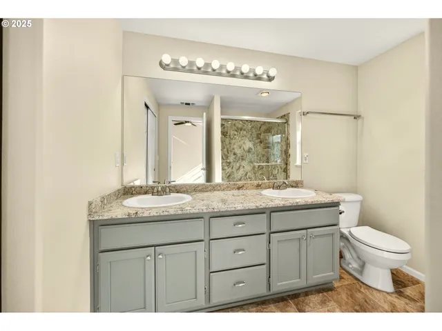 a bathroom with a granite countertop sink a toilet and a mirror