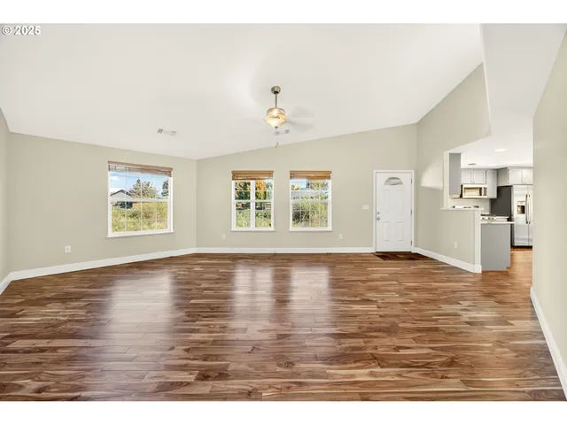 a view of an empty room with window and wooden floor