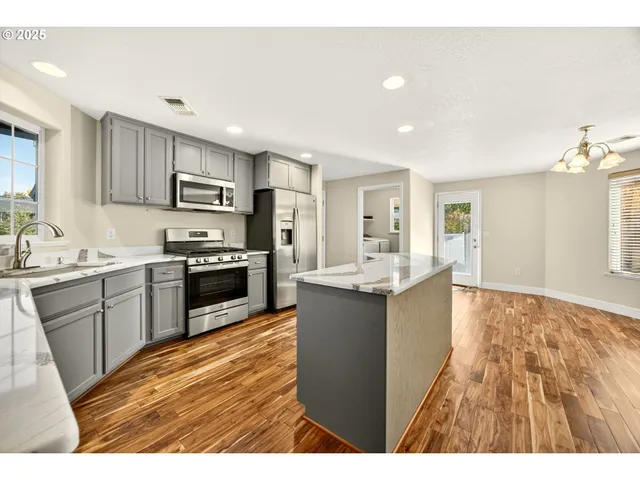 a kitchen with kitchen island granite countertop a sink cabinets and stainless steel appliances