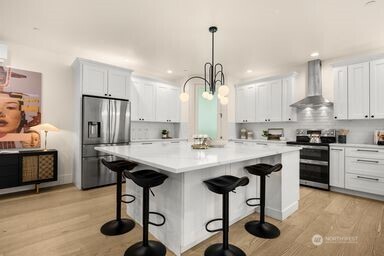 2411 Southwest 346th Street Federal Way, WA 98023 - Photo 9 of 30 a kitchen with stainless steel appliances kitchen island a table chairs sink and cabinets
