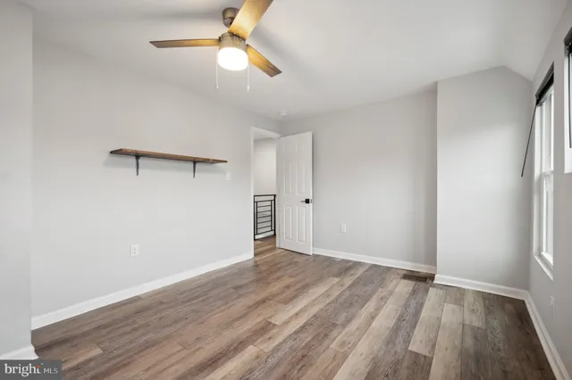 an empty room with wooden floor fan and windows