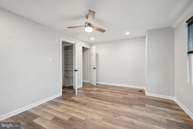 an empty room with wooden floor and ceiling fan