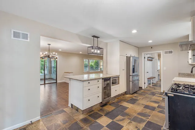 a kitchen with granite countertop a refrigerator and a stove top oven