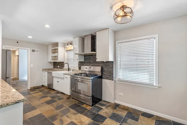 a kitchen with stainless steel appliances granite countertop a stove a sink and a refrigerator