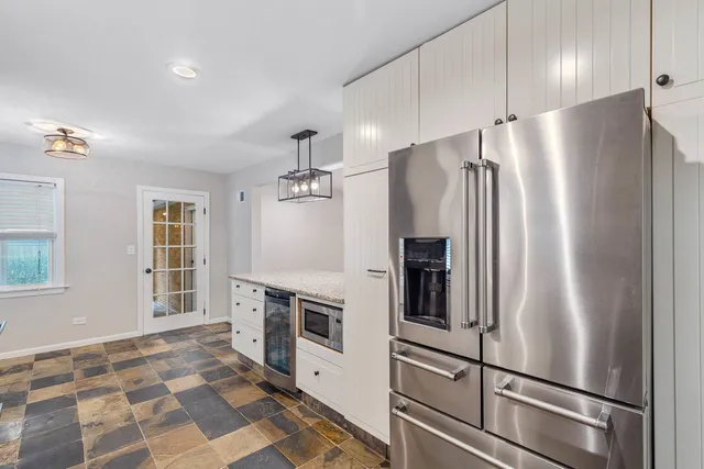 a metallic refrigerator freezer sitting inside of a kitchen
