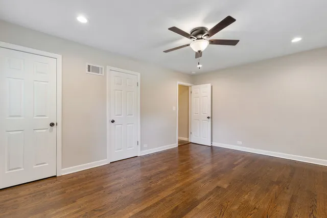 an empty room with wooden floor and ceiling fan